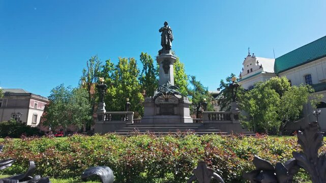Statue of Adam Mickiewicz in a sunny park, with beautiful greenery and clear skies