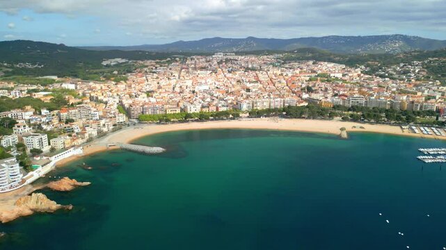 Aerial view showcasing the picturesque coastal town of sant feliu de guixols on the costa brava, spain, highlighting the vibrant cityscape nestled against the turquoise mediterranean sea