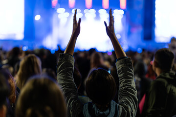 Hands raised up at big open air concert with the crowd background. girl applauds a musical group at a street concert.