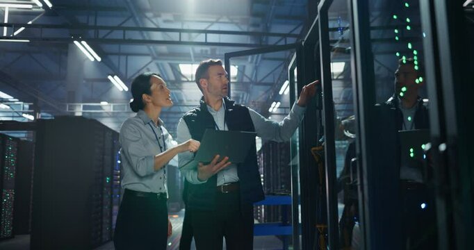 Female Data Center eBusiness Manager and Male IT Specialist Having a Conversation and Using Laptop Computer. Two Information Technology Engineers Discussing Cloud Computing Server Farm