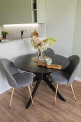 Dining area within a new European home's open concept living space. Wooden table, upholstered chairs, and parquet floor are present. A modern interior solution for contemporary residential properties.