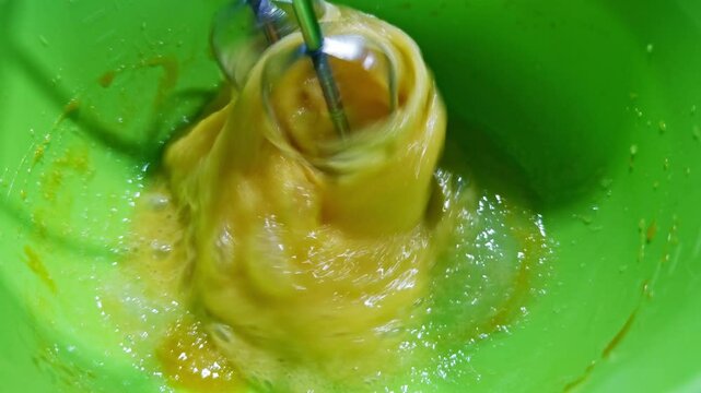Mixer beats eggs in bowl . Cook whipping eggs with whisk