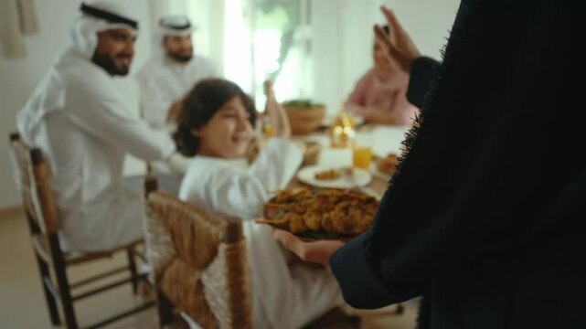 Emirati family sharing a meal together during the holy month of ramadan, passing dishes and engaging in conversation around a beautifully set table