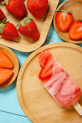 top view strawberry slices popsicle with couple of bites with fresh strawberries vertical composition