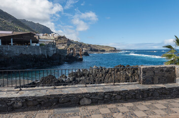 Old fish factory building at center of Garachico old town with sea pools and lava rocks at Tenerife canary island, Spain. Blue sky white clouds background