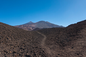Winter view on colorful volcano Pico del Teide with snow spots from hiking trail Samara. Mountains and lava fields against blue sky. El Teide National Park, Tenerife, Canary Islands, Spain
