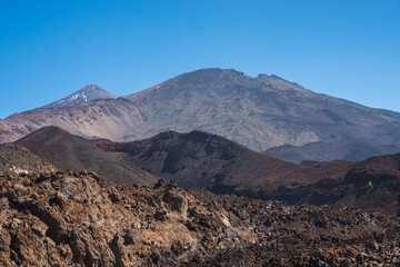 Winter view on colorful volcano Pico del Teide with snow spots from hiking trail Samara. Mountains and lava fields against blue sky. El Teide National Park, Tenerife, Canary Islands, Spain