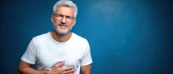 Senior man expresses digestive discomfort against bright blue backdrop