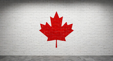 Red canadian maple leaf painted on white brick wall symbolizing canadian identity, freedom and urban pride