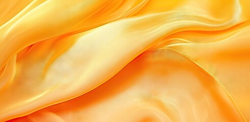 Obraz premium A vibrant close-up of flowing yellow and orange silk fabric. showcasing its smooth texture and gentle waves. ideal for fashion or interior design applications