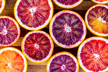 Red blood halved oranges close up on a wood background. Top view. Flat lay of fresh orange citrus...