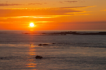 Fototapeta premium Sunset vivid orange and red over Burhou island and the sea off the coast of Alderney in the Channel Islands