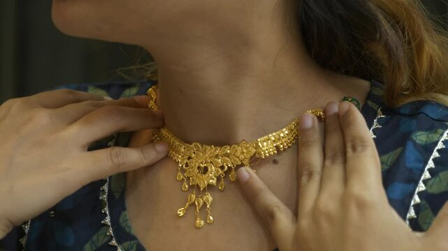 Young asian woman trying on a designer gold necklace, 18k HUID certified gold necklace, Closeup