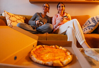 A teenagers are sitting on the couch in the living room and a piece of pie