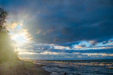 Dark sky over the sea. Low clouds over the water in the bay. Background with a tense panorama of the coast before a storm at sunset.