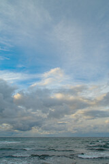 Dark sky over the sea. Low clouds over the water in the bay. Background with a tense panorama of nature before a storm at sunset.