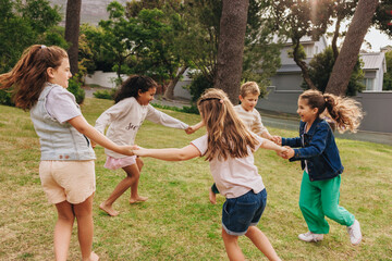 Fototapeta premium Children playing together in a grassy park during a sunny day