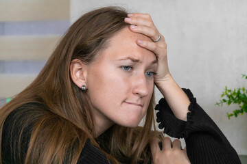 Obraz premium Young woman with long brown hair wearing a black dress touching her forehead with her hand while suffering from a headache, expressing sadness, grief, stress, and frustration