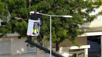 Workers in aerial work platform check street light in residential area