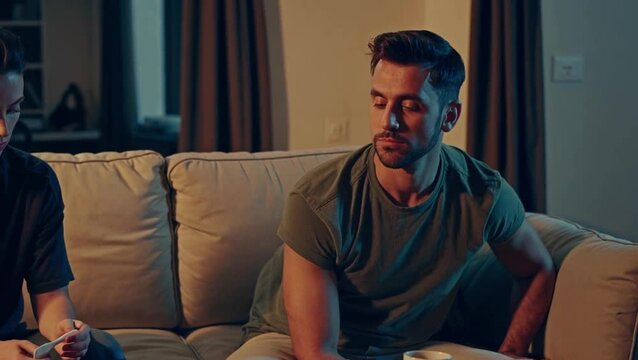 Man sitting on sofa turning away during serious conversation &mdash; emotional distance and conflict