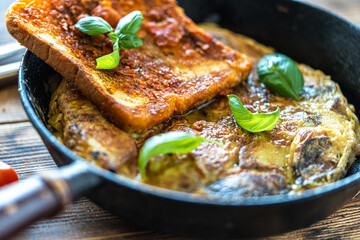 Traditional spanish breakfast potato tortilla and tostado pan con tomate. Potatoes and croutons with garlic and tomato sauce in a cast iron frying pan on a rustic wooden background. High quality photo