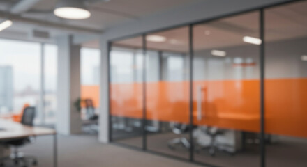 Beautiful blurred background of a modern office interior in gray tones with panoramic windows, glass partitions and orange color accents.