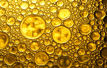 Abstract close-up of golden oil bubbles on liquid surface, ideal for art, science, texture, and...