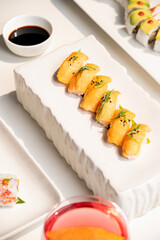 Wild salmon nigiri with silky salmon, toasted sesame, and ginger—elegantly plated on white and paired with a vibrant red cocktail, set against a soft, upscale white background. 