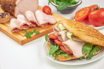 Fresh sandwich with roast pork, vegetables, and crispy flatbread on a white plate. copy space