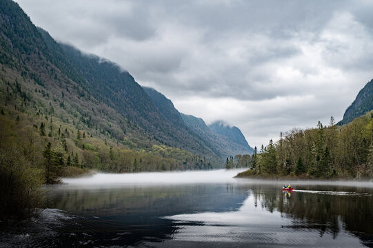 Adventurers canoeing through Jacques Cartier river on a cloudy day, Jacques Cartier national park, Quebec, Canada