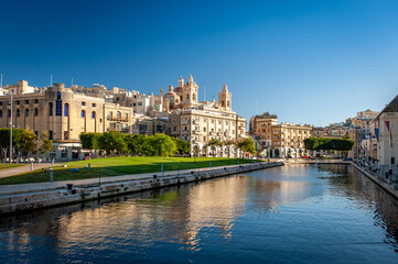 Obraz premium Spectacular view of seaport Vittoriosa and St. Lawrence's Catholic Church. Location place Birgu harbour, Malta, Europe. Photo wallpapers. Golden hour.