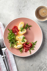 Delicious french omelette stuffed with cheese served with fresh greens and ham top view. Healthy diet food concept. Protein breakfast