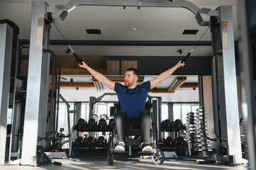 Fototapeta premium Man in wheelchair exercising with cable machine in gym