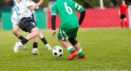 Intense Youth Soccer Match in Action as Player in Green Dribbles the Ball Past Defenders on a Grass Outdoor Field