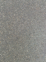 Close-up texture of gray asphalt road surface with small stones and cracks, detailed grunge background for construction and design