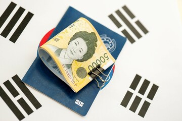 South Korean won money bills in big amount and passport lies on South Korea flag close up. Finance...
