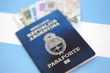 Argentine pesos money bills in big amount and passport lies on Argentina flag close up