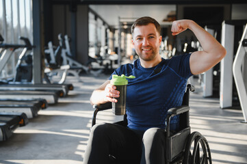 Man with disability, athlete showing his biceps in a wheelchair at the gym