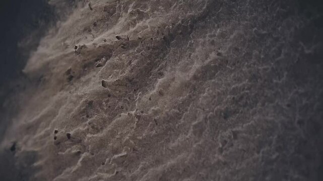 Dust particles swirl and settle in a close-up view of an indoor surface as light illuminates the texture