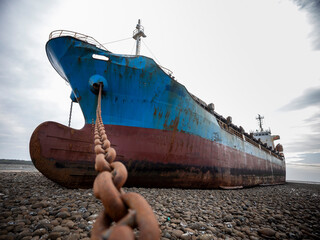 A cargo ship ran aground on the coast after a typhoon. Stranded ship is a huge risk of marine...