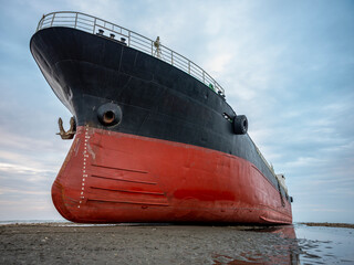 A cargo ship ran aground on the coast after a typhoon. Stranded ship is a huge risk of marine...