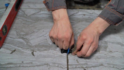 Construction worker uses a tile leveling system to ensure even tile spacing during installation