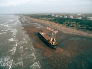 A cargo ship ran aground on the coast after a typhoon. Stranded ship is a huge risk of marine...