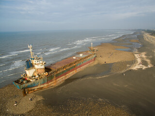 A cargo ship ran aground on the coast after a typhoon. Stranded ship is a huge risk of marine...