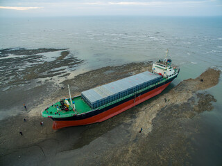 A cargo ship ran aground on the coast after a typhoon. Stranded ship is a huge risk of marine...