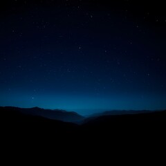 Distant mountains are silhouetted beneath a vast, dark blue night sky filled with twinkling stars.