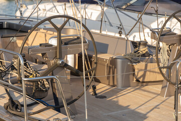 Sailing yacht cockpit featuring steering wheel and ropes, showcasing nautical equipment and wooden deck in a serene maritime environment