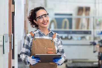 Woman wearing a plaid shirt and apron is smiling and holding a tool