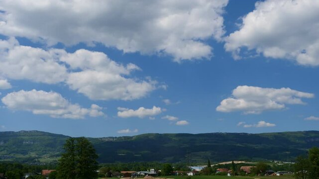 Time-lapse footage of the white clouds rolling in the blue sky over a rural village, Switzerland