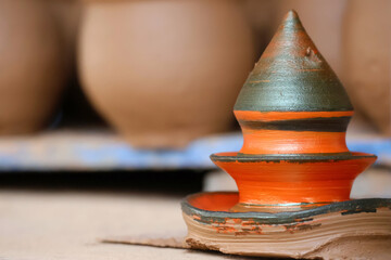 Colorful wet clay art moulded by indian potters and kept for drying with bokeh background of other clay pots.Image for pottery,artwork,workshops,webinars,creation,craft.Complex clay sculpture display